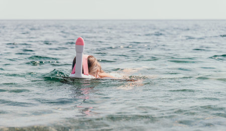 Young happy woman in white bikini and wearing pink mask gets ready for sea snorkeling. Positive...