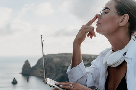 Woman sea laptop. Business woman, freelancer with laptop working over blue sea beach. Happy smiling girl relieves stress from work. Freelance, remote work on vacation, digital nomad, travel conceptの写真素材