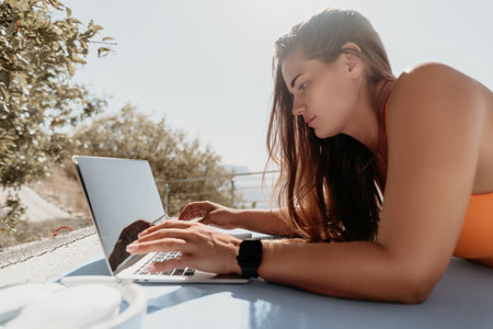 Young Woman Working on Laptop by the Seaの写真素材
