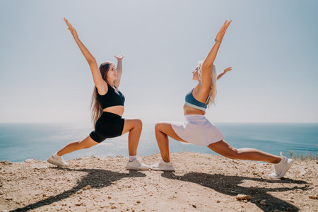 Two Women in Athletic Wear Performing a Yoga Pose on a Cliffの写真素材