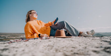 Woman Relaxing on a Cliffside with a Phone
