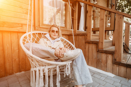 Woman Relaxing in a Hanging Chair on a Wooden Patioの写真素材