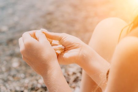 Woman eating milky almond nuts. A young caucasian woman chopping fresh green almond after morning fitness yoga near sea. Only hands are visibly. Healthy vegan food. Slow motion. Close upの写真素材