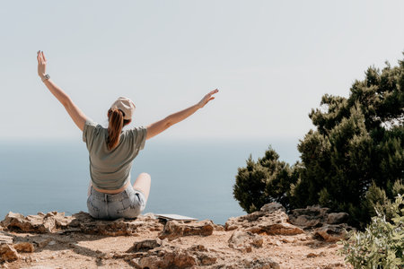 Woman Celebrating on a Clifftop with Arms Raisedの写真素材