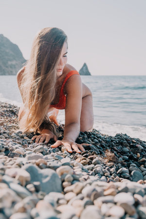 Woman in Red Bathing Suit on a Pebble Beachの写真素材
