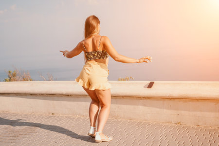 Woman summer dance. Silhouette of a happy woman who dances, spins and raises her hands to the sky. A playful young woman enjoys her happy moment dancing in the rays of the golden sun.の写真素材