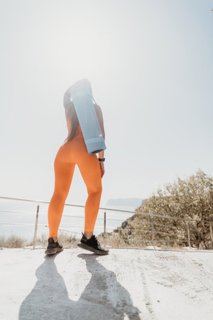 Woman in Orange Outfit with Yoga Mat by the Sea