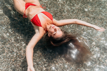 Woman swimming floating in calm sea. Happy smiling woman with long hair and fit body enjoys sea beach during summer vacation holidays. Concept of body image and fitness, enjoying a serene beach.の写真素材