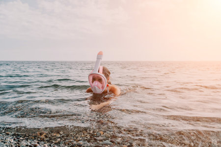 Young happy woman in white bikini and wearing pink mask gets ready for sea snorkeling. Positive...