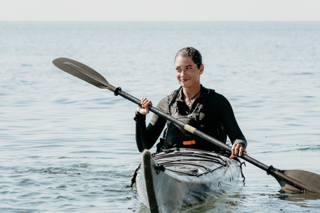 Woman sea kayak. Happy smiling woman in kayak on ocean, paddling with wooden oar. Calm sea water and...
