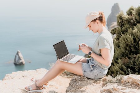 Woman on a Cliffside Using a Laptop and Smartphone