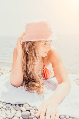 Happy young woman sunbathing or tanning on a seaside beach during summer vacation. smiling tourist...