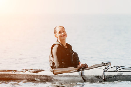 Woman sea kayak. Happy smiling woman in kayak on ocean, paddling with wooden oar. Calm sea water and horizon in background. Active lifestyle at sea. Summer vacation.の写真素材