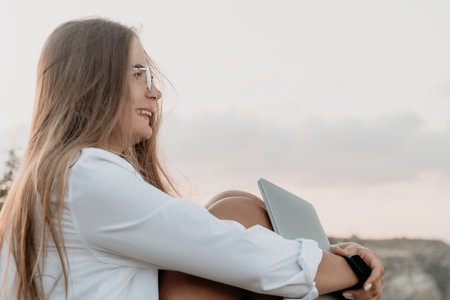 Woman sea laptop. Business woman, freelancer with laptop working over blue sea beach. Happy smiling girl relieves stress from work. Freelance, remote work on vacation, digital nomad, travel conceptの写真素材