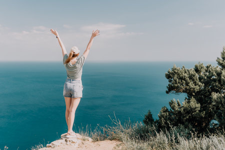 Woman Celebrating Freedom on a Cliff overlooking the Seaの写真素材