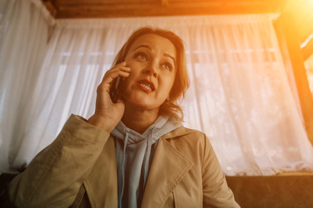 A Woman on a Phone Call in a Room with White Curtainsの写真素材