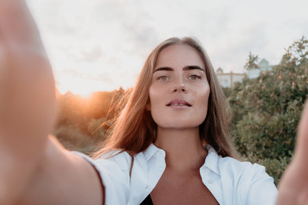 Amber Golden Hour Close up of a woman bathed in golden hour light making selfie on sunset in summer...