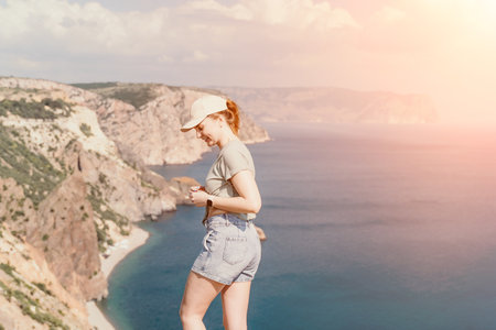 Woman in a Cap Standing on a Cliff Overlooking the Oceanの写真素材