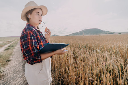 Woman in a Hat and Plaid Shirt Stands in a Wheat Fieldの写真素材