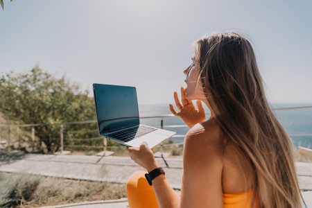 Young Woman Using Laptop with Sea Viewの写真素材