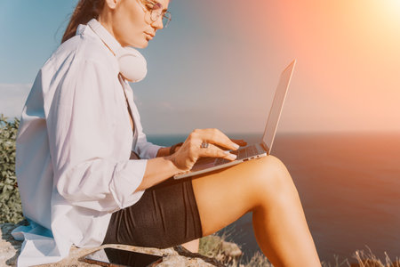 Woman sea laptop. Business woman, freelancer with laptop working over blue sea beach. Happy smiling girl relieves stress from work. Freelance, remote work on vacation, digital nomad, travel conceptの写真素材