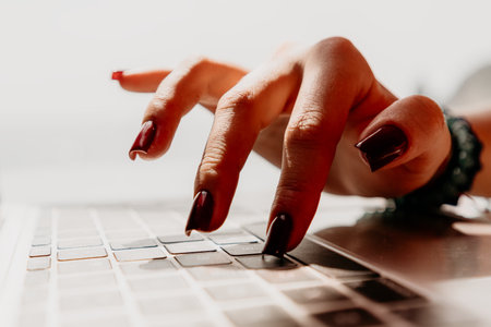 Hands, Keyboard, Typing: Womans hand with red nails typing on a laptop keyboard.の写真素材