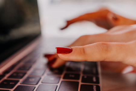 Hands Typing Laptop Keyboard Close Up - Womans hands with red nail polish typing on a laptop keyboard.の写真素材