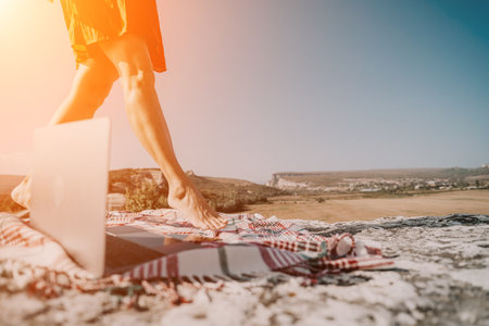 Barefoot Woman Walks Past Laptop on a Blanket on a Cliffside