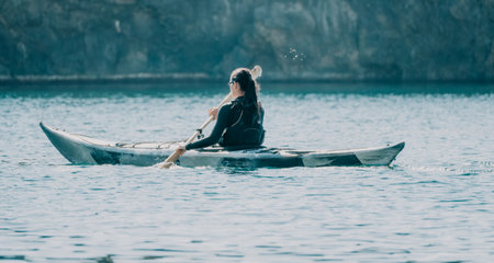 Woman sea kayak. Happy smiling woman in kayak on ocean, paddling with wooden oar. Calm sea water and horizon in background. Active lifestyle at sea. Summer vacation.の写真素材