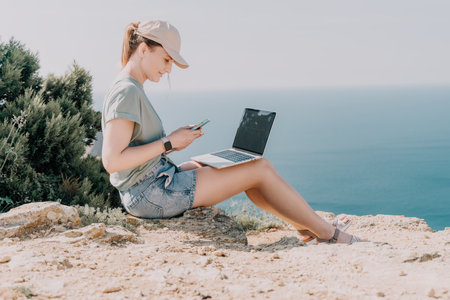 Woman Working on Laptop and Phone on Cliffsideの写真素材