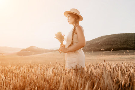 Woman wheat field. Agronomist, Woman farmer check golden ripe barley spikes in cultivated field. Closeup of female hand on plantation in agricultural crop management concept.の写真素材