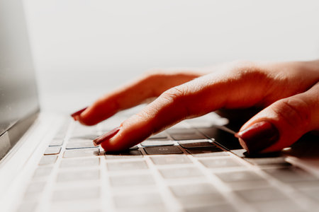 Hand Typing Keyboard Laptop - Closeup of a hand typing on a laptop keyboard with red nail polish.の写真素材