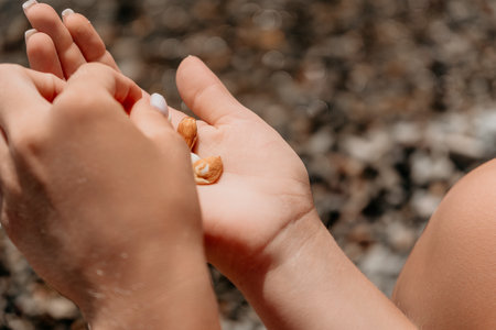 Woman eating milky almond nuts. A young caucasian woman chopping fresh green almond after morning fitness yoga near sea. Only hands are visibly. Healthy vegan food. Slow motion. Close upの写真素材
