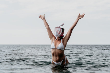 Woman Beach Ocean - A woman in a white bikini stands in the ocean with her arms raised.の写真素材