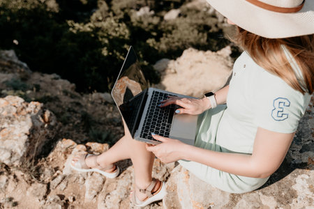 Woman Working on Laptop on Rocky Cliffの写真素材