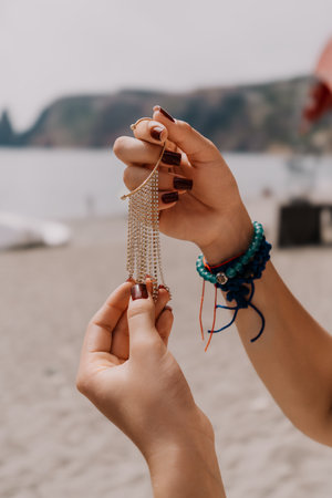 Hands Jewelry Beach - Woman holding silver chain necklace on beach.の写真素材