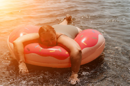 Woman Donut Float Beach Summer Vacation Relaxing on Pink Inflatable Ringの写真素材