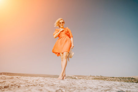 Woman in a Red Dress Walking on a Rock Cliffの写真素材