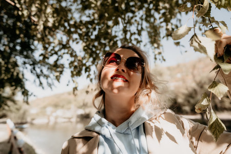 Woman in Sunglasses Gazing Upwards in a Parkの写真素材