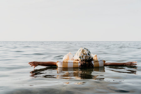 Woman, Inflatable Raft, Ocean - A person floats on a striped inflatable raft in a calm sea.の写真素材