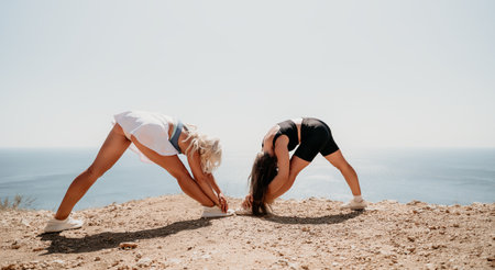 Two Women Stretching on a Cliffside Overlooking the Oceanの写真素材