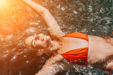 Woman swimming floating in calm sea. Happy smiling woman with long hair and fit body enjoys sea beach during summer vacation holidays. Concept of body image and fitness, enjoying a serene beach.の写真素材