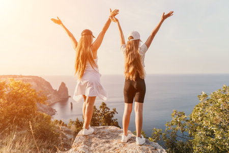 Two Women Celebrating on a Mountaintop Overlooking the Oceanの写真素材