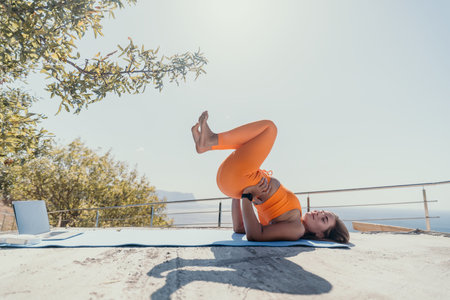 Woman Practicing Yoga Outdoors with a Laptop in the Backgroundの写真素材