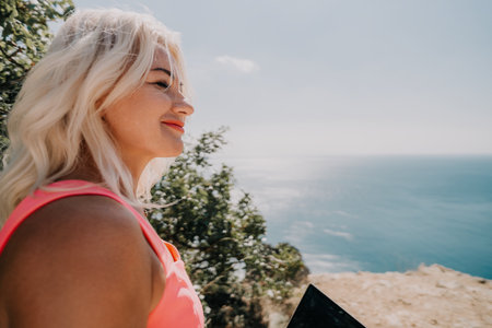 Woman Gazing at the Ocean with a Laptopの写真素材
