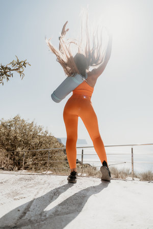 Woman in Orange Leggings with Yoga Mat Standing on a Cliffside