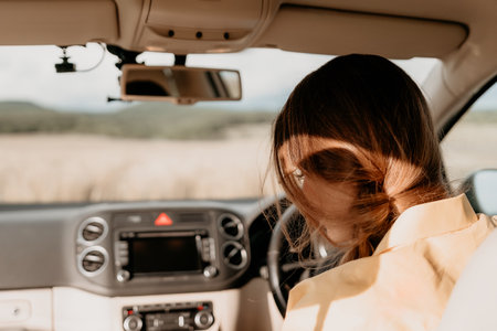 Woman in a Car with a Sunlit Backの写真素材