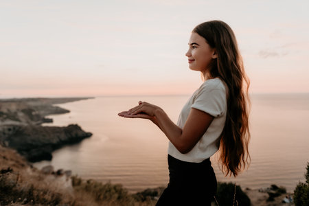 Young Woman in White and Black Clothing Admires Sunset Over the Seaの写真素材