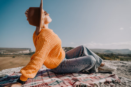 Woman in a Yellow Sweater and Hat Relaxing on a Blanketの写真素材