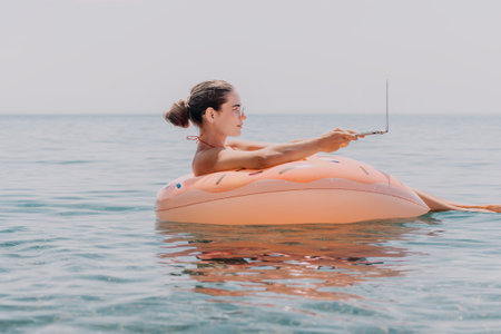 Woman Laptop Float Ocean - A woman works on her laptop while floating on an inflatable ring in the ocean.の写真素材